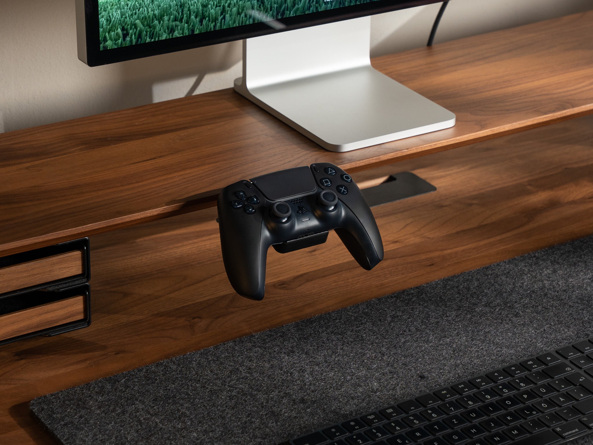 Detail-Aufnahme vom BALOLO Controller Halter montiert am Setup Cockpit Monitorständer in Nussbaum. In ästhetischem Office-Setup mit einem PlayStation 5 Controller in der Controller Station. @expand
