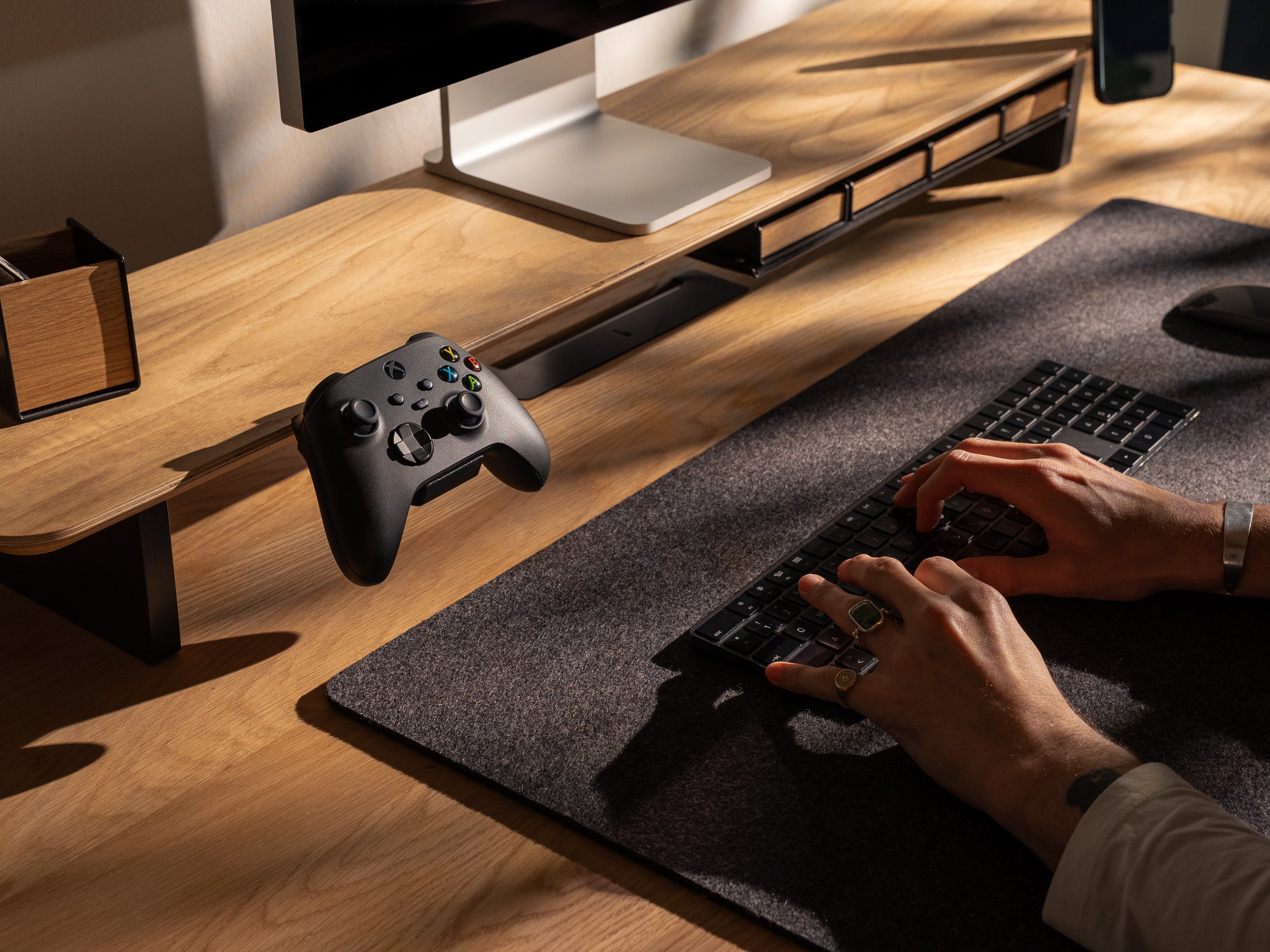 Detail-Aufnahme vom BALOLO Controller Halter montiert am Setup Cockpit Monitorständer in Eiche. In ästhetischem Office-Setup mit einem Xbox Controller in der Controller Station. @expand