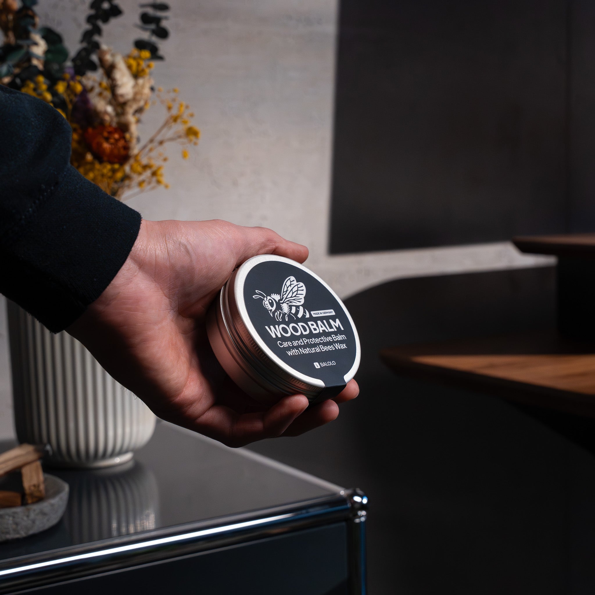 Holzpflege wird von Hand gehalten in modernem Office Setting. Stehschreibtisch im Anschnitt.