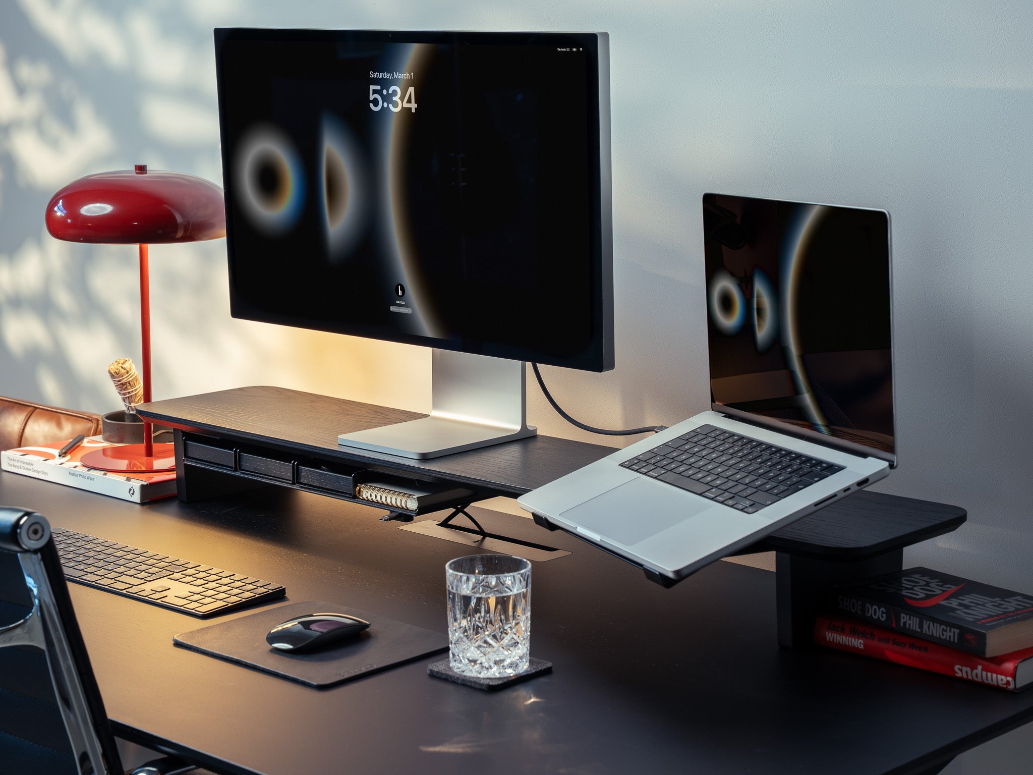 Setup Cockpit Monitorständer aus schwarz gefärbter Eiche mit Anbauteilen: Laptophalter, großes Fach mit Stiftablagen, Kabelmagneten, Mauspad Leder, Desk Coaster, Stifthalter. Abgebildet auf schwarzem Schreibtisch in modernem Office Setting. @expand