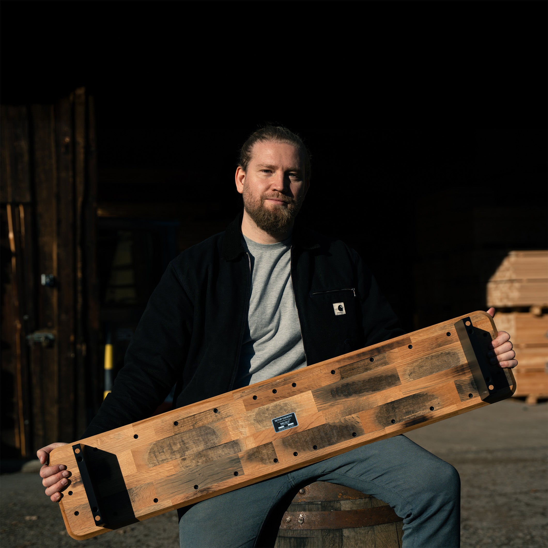 BALOLO Gründer mit Setup Cockpit als Whiskey Barrel Edition, sitzend auf einem Whiskey Fass vor Holzlager.