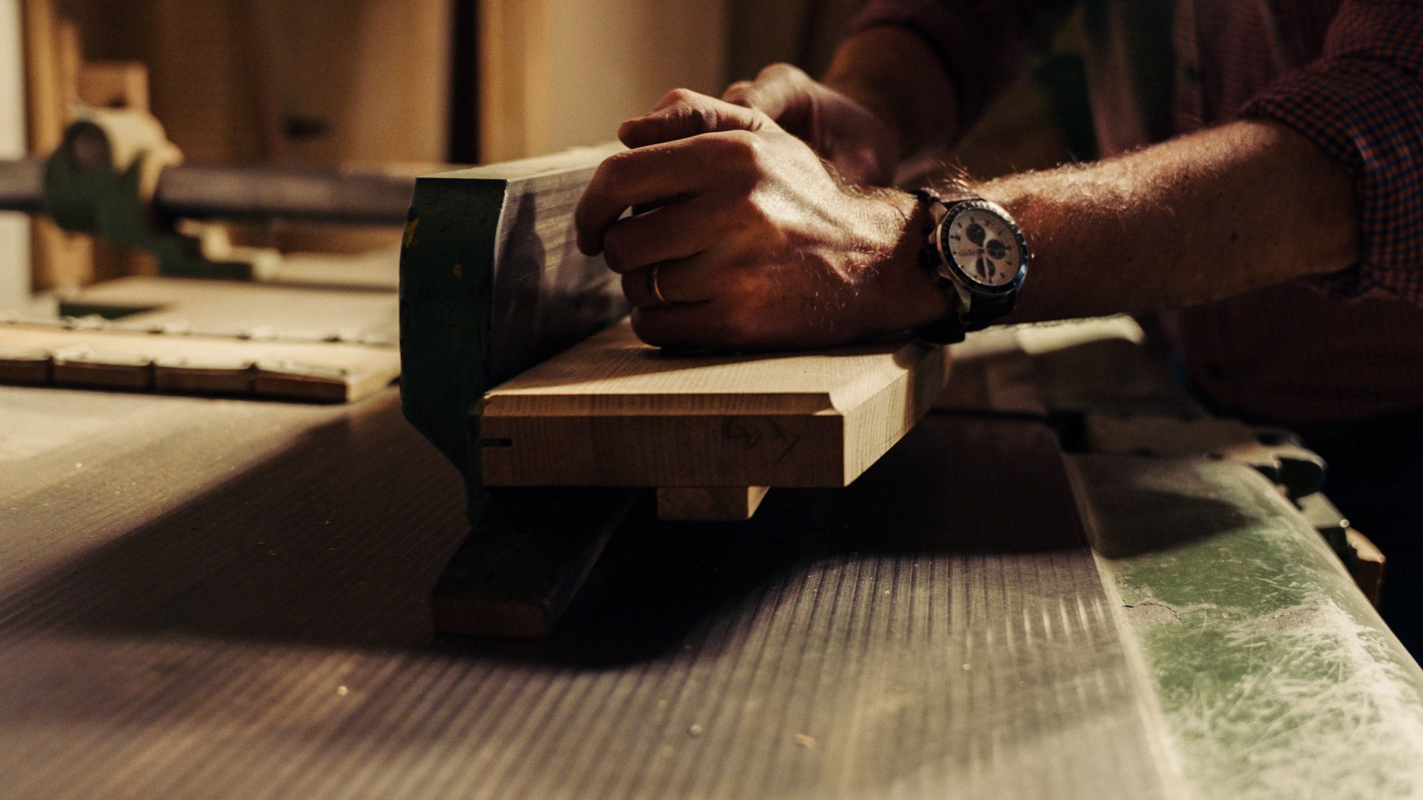 Stimmungsvolle Nahaufnahme eines Handwerkers, der eine Fassdaube auf einer Abrichte begradigt.