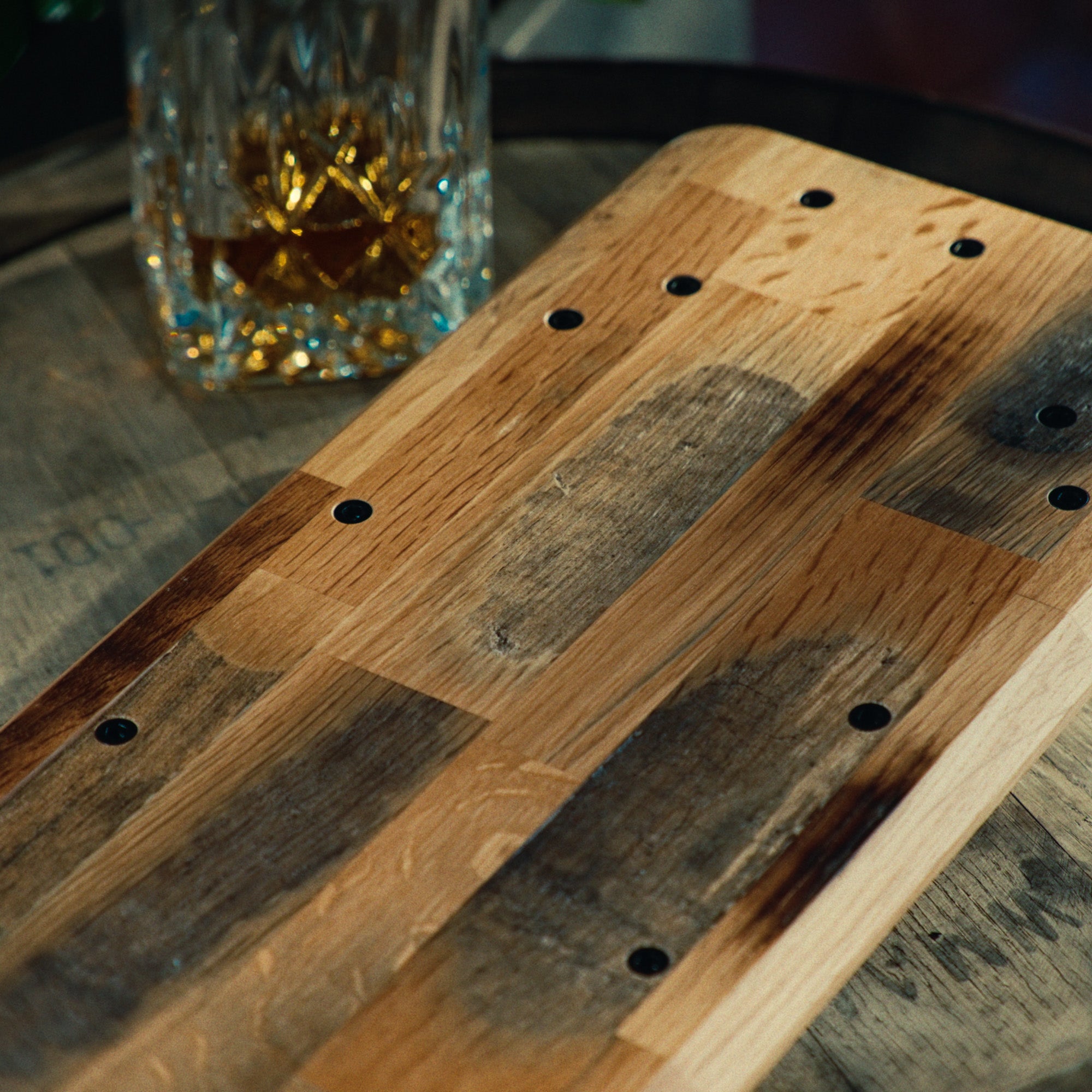 Detailaufnahme von Unterseite des Setup Cockpits der Whiskey Barrel Edition. Fokus auf Charakteristik des Holzes. Inszeniert auf Whiskeyfass mit Karaffe.