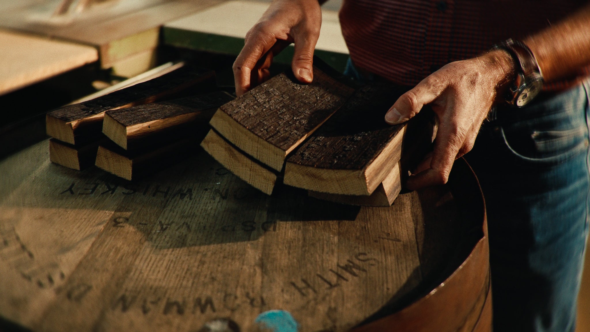 Poster Image des Kampagnenvideos. Handwerker leg zugeschnittene Fassdauben auf Whiskey Fass.